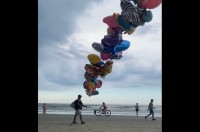 ビーチを歩くバルーン売り。果てしなくつながるバルーンの束が圧巻の映えを生む！【海外・動画】